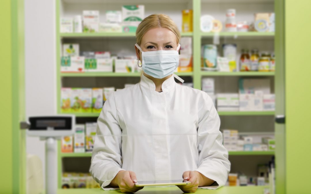 Pleasant professional young female pharmacist with surgical mask smiling